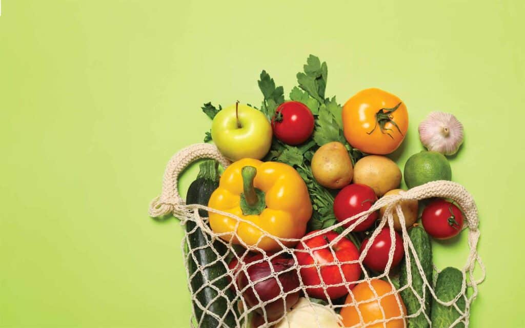 fresh fruits and vegetables in a reusable mesh produce bag
