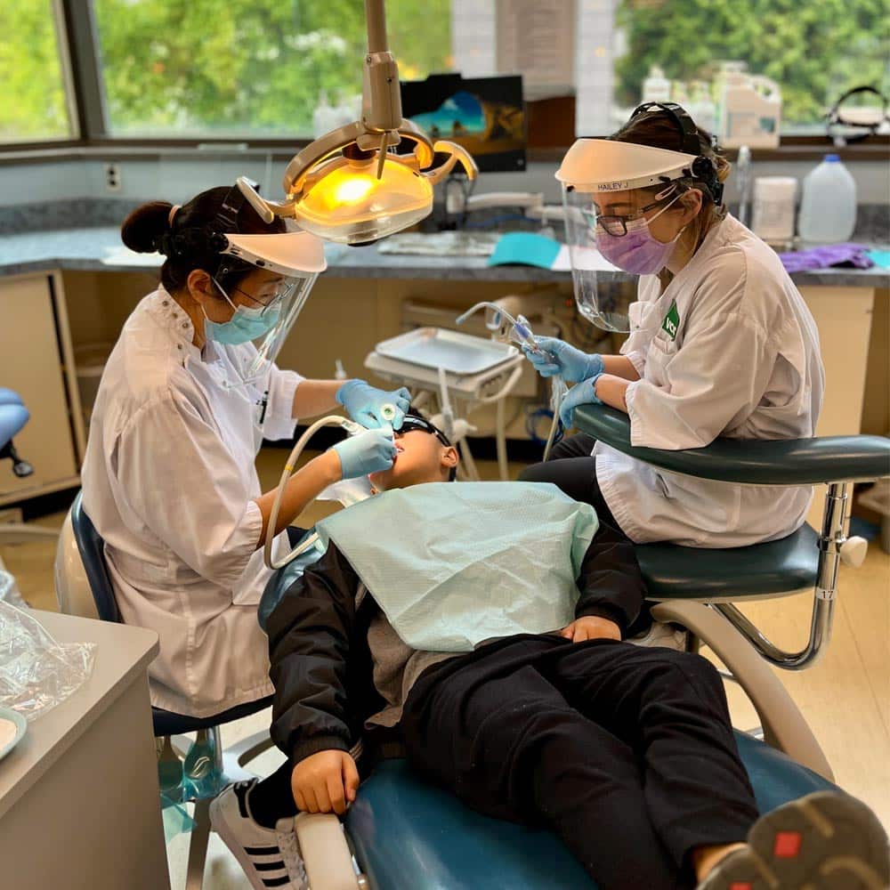 Dental students performing a dental examination on a young patient