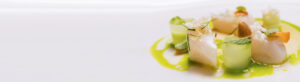 Gourmet dish with cucumber rolls, a creamy protein, garnishes, and a green sauce on a white plate.