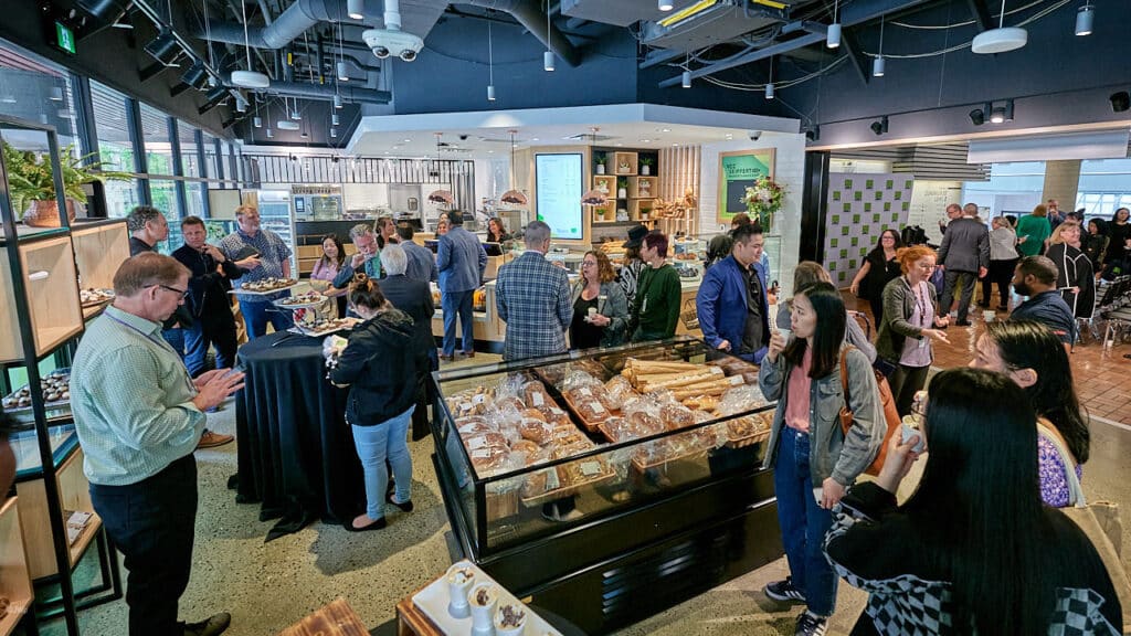 A large group of people gathered at Seiffert Bakery, browsing food displays.