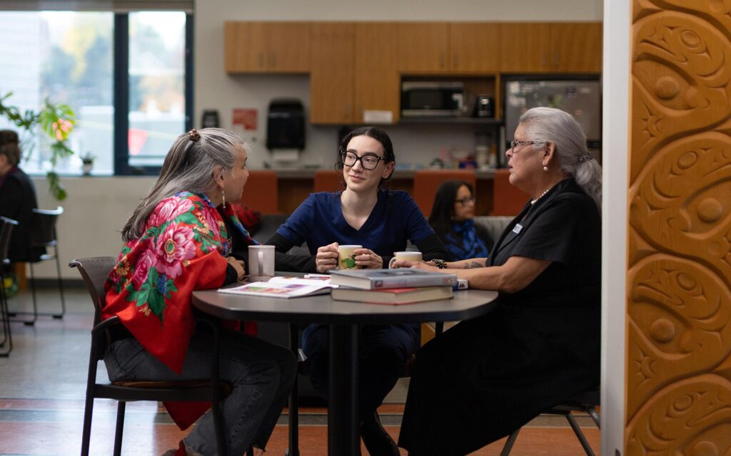 Three women having coffee in the kitchen of the indigenous space wit