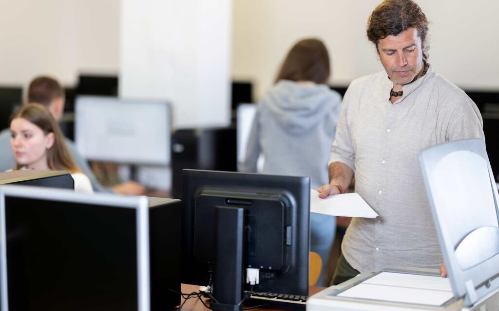 A man using the photocopier in a computer lab