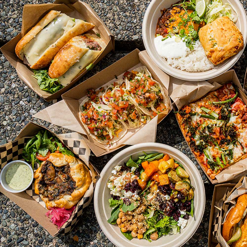 An overhead view of various takeout containers featuring tacos, pizza, grain bowls, sandwiches, burgers, and salad.