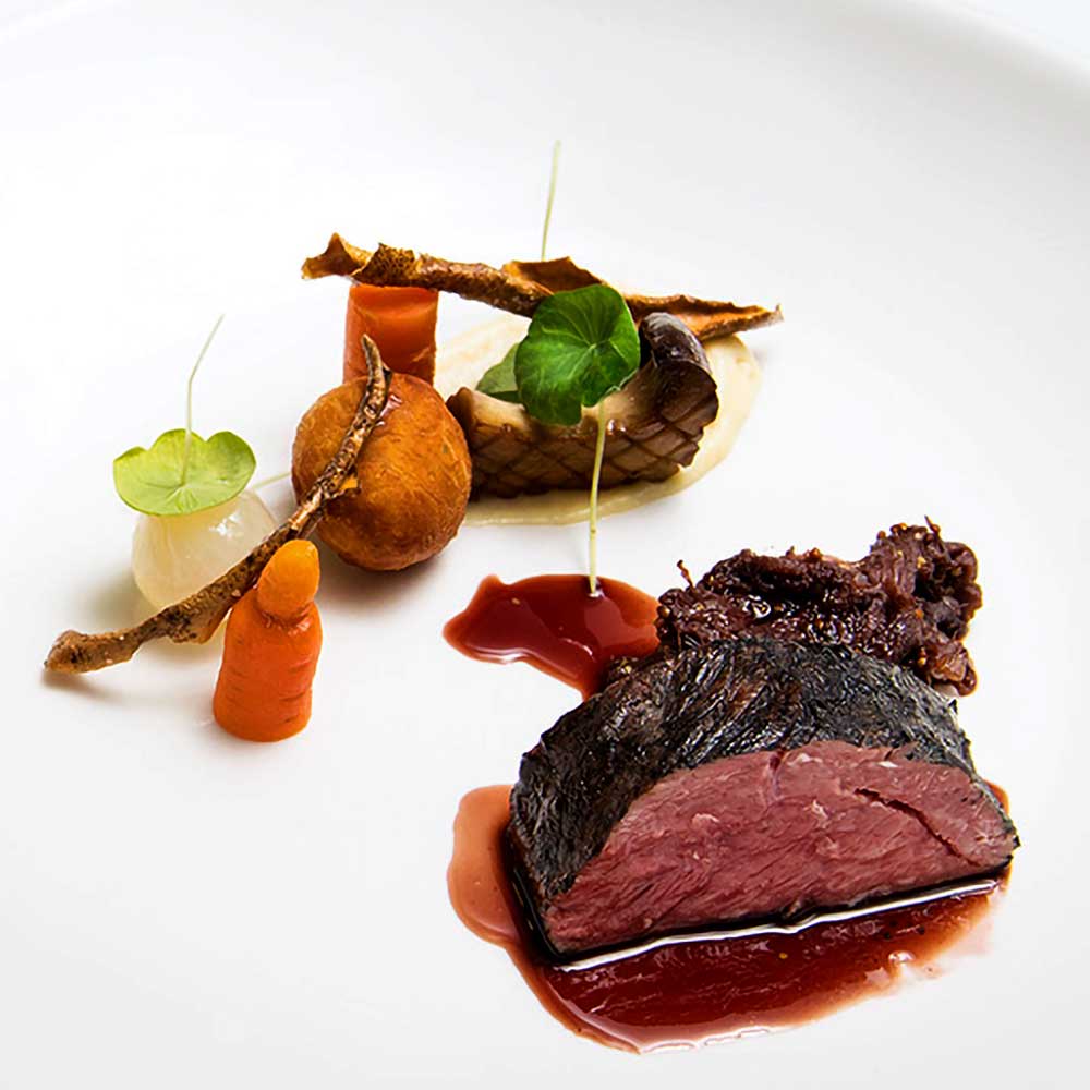 A tender, medium-rare steak served with roasted carrots and a rich red wine reduction.