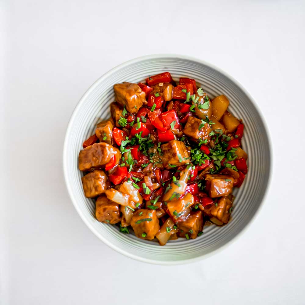 A hearty, savory braise of tender meat chunks and red bell peppers topped with fresh parsley.
