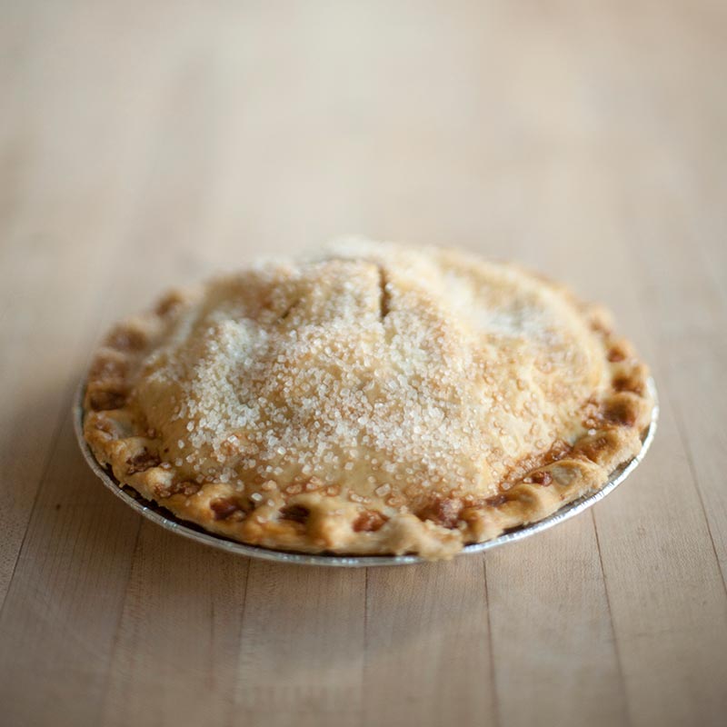 A freshly baked apple pie with a golden-brown fluted crust topped with a dusting of coarse sugar