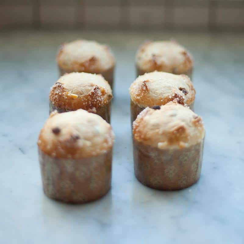 Two rows of freshly baked muffins in decorative paper liners on a marble surface.