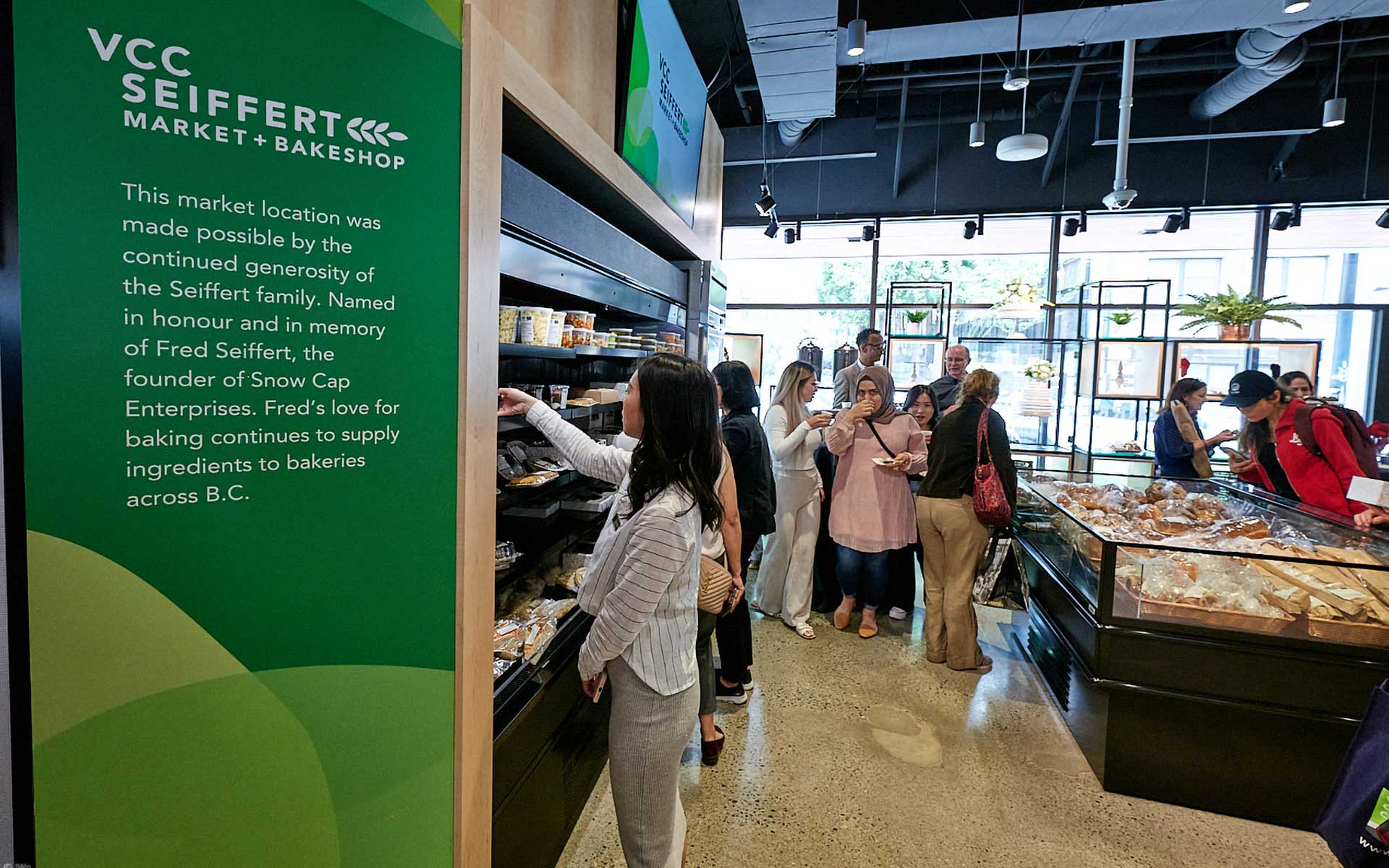 Customers browsing the refrigerated and baked goods sections inside the VCC Seiffert Market and Bakeshop.