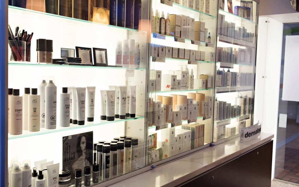 Glass shelves filled with various professional hair care and skincare products.