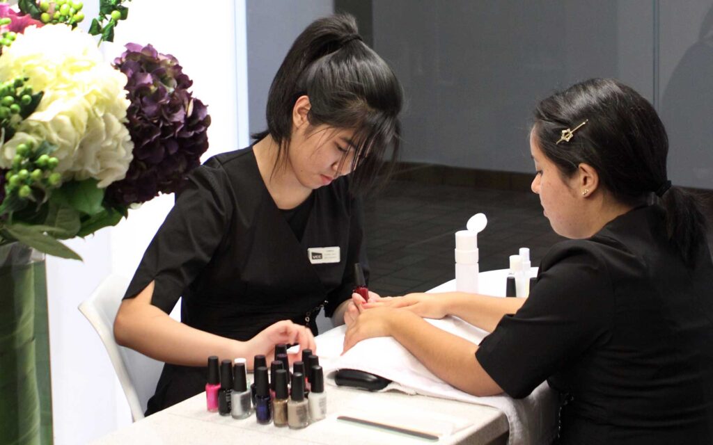 A client is getting their nails done by a VCC salon and spa student