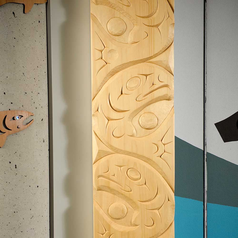 indigenous art of carved wooden panel featuring salmon motifs.