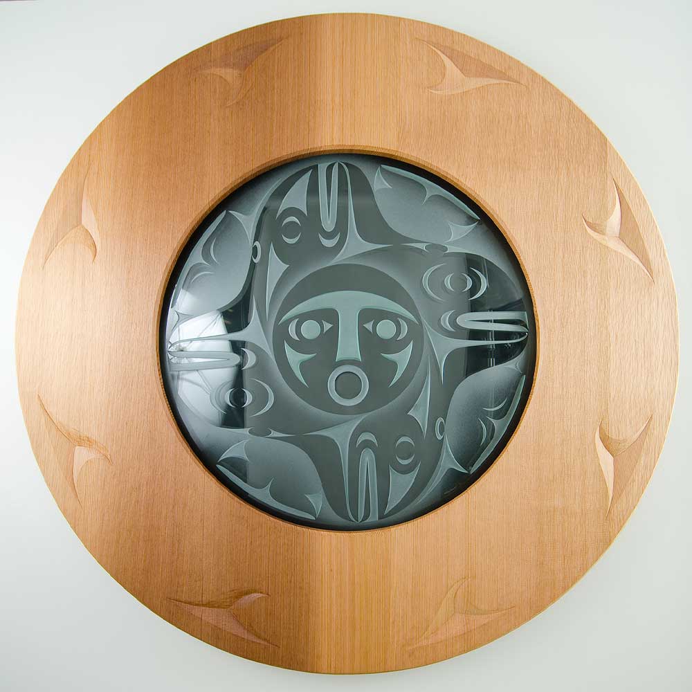 Indigenous artwork is a large, circular panel featuring a central face representing the sun, executed in a traditional formline style.