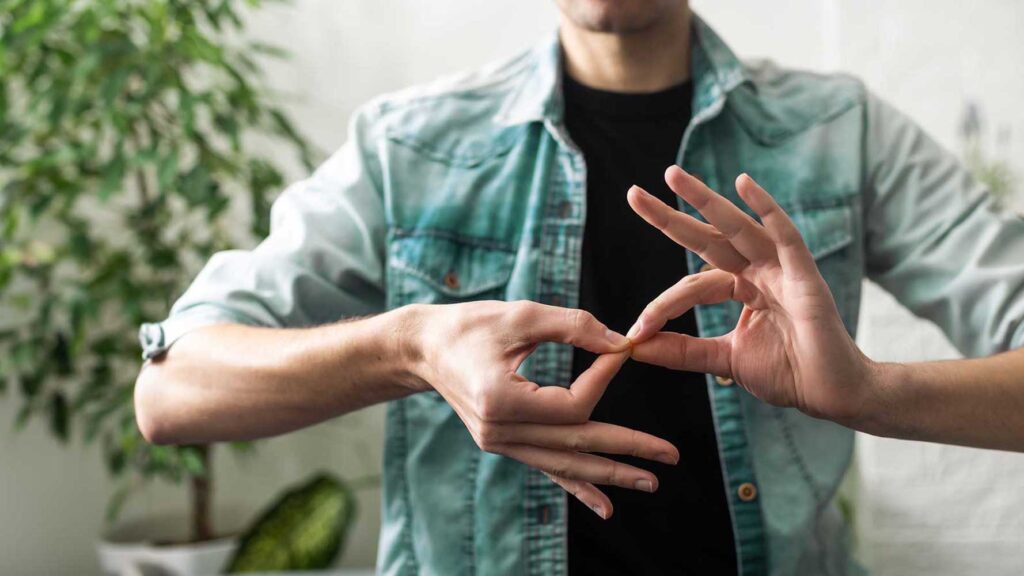 A close-up of a person's hands performing a precise sign language gesture