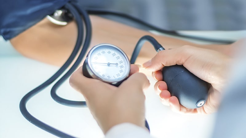 Person measuring blood pressure using a manual sphygmomanometer. The cuff is wrapped around an arm, and a hand squeezes the bulb.