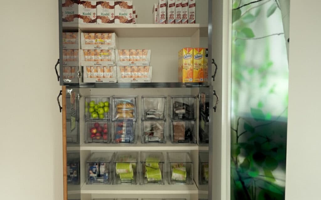 Open pantry shelves stocked with various canned goods, packaged foods, and jars of bulk items.