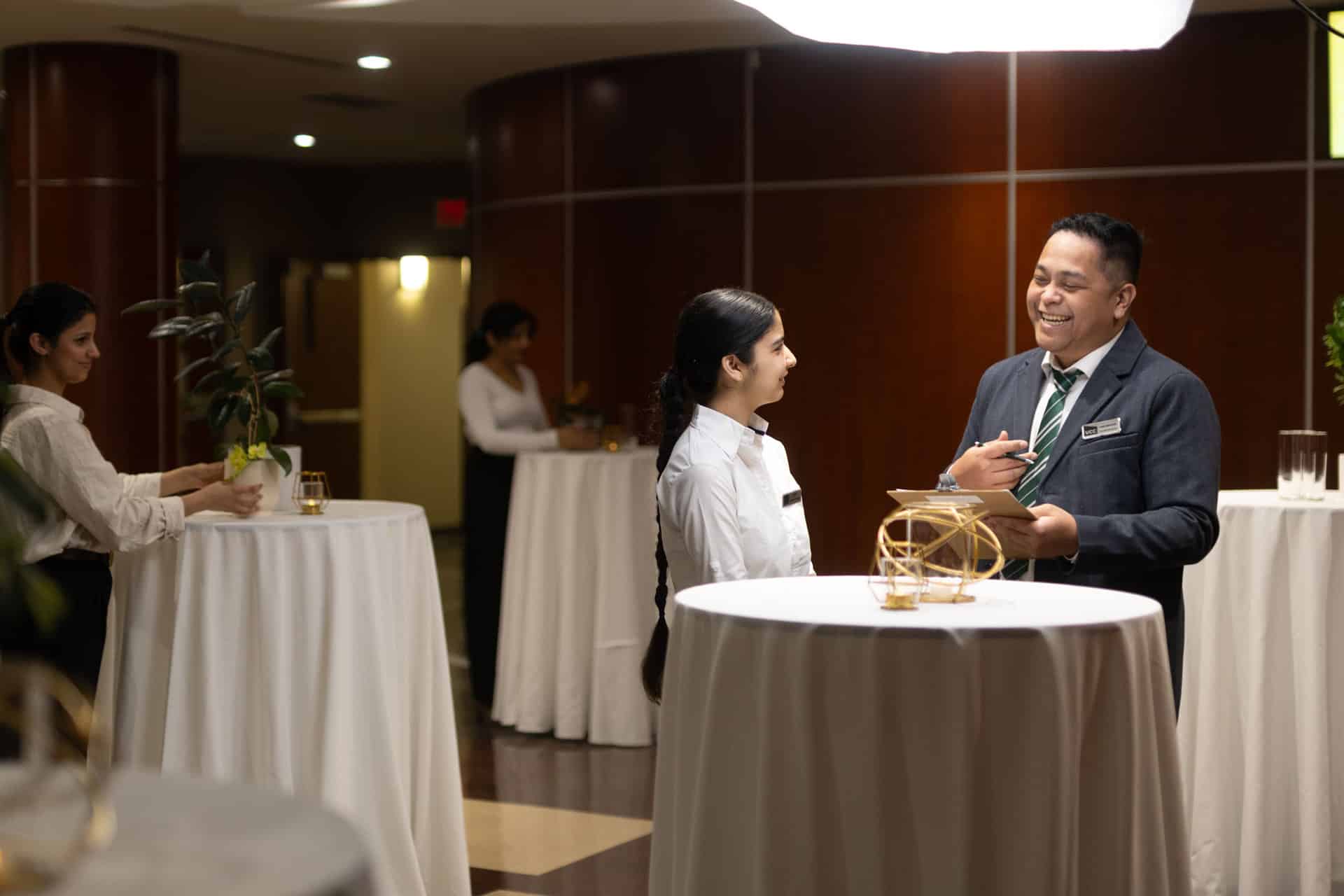 Hospitality program students discussing service tasks in a training restaurant