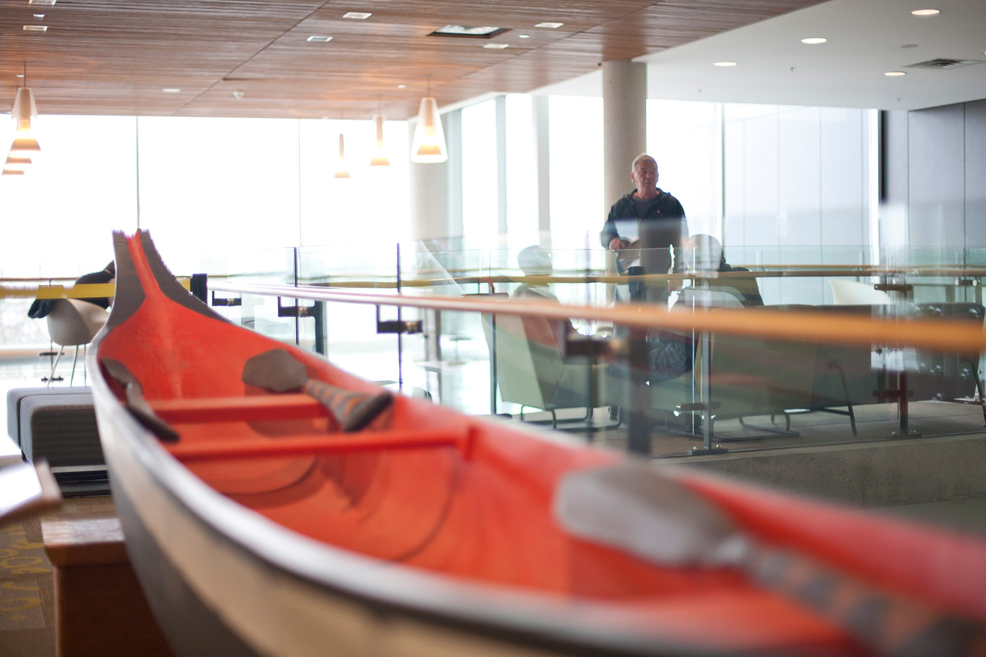 Indigenous art of a real size carved canoe in black and red and white with 2 wooden paddles