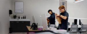 Hairstyling apprentices practice techniques on mannequin heads at individual workstations in a modern training salon.